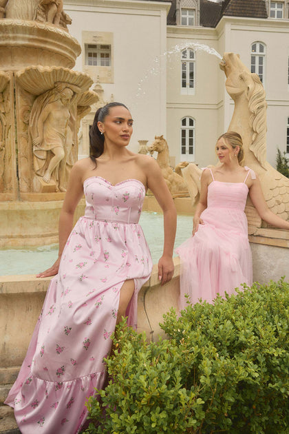 Model (L) in Valentina Satin Floral Print Dress in Baby Pink Petit Rose. Model (R) in Eloise Tulle Dress in Baby Pink.